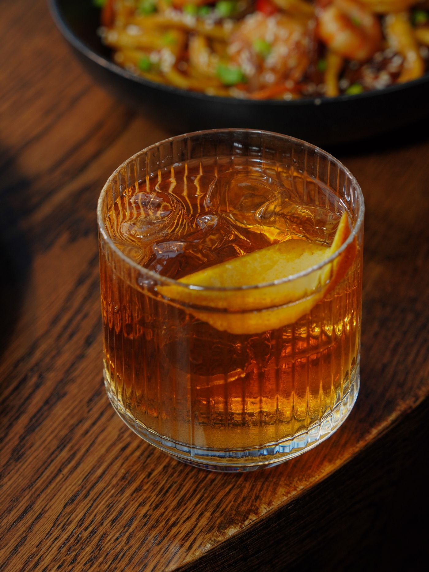 Old Fashioned cocktail with orange peel on a wooden table