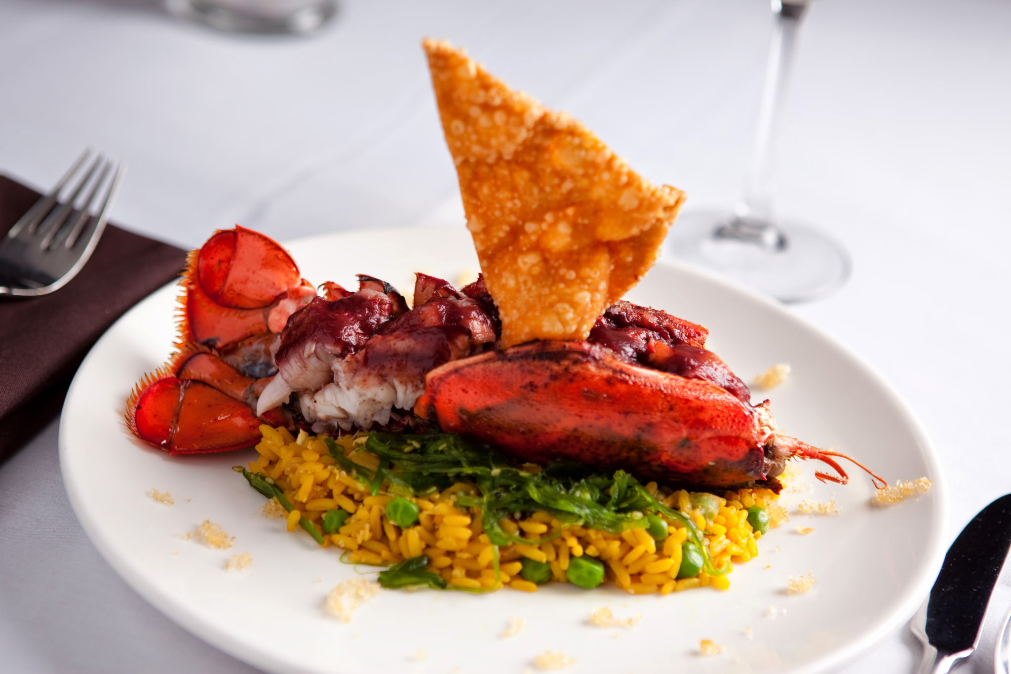 Plated lobster with golden rice, greens, and a crisp garnish